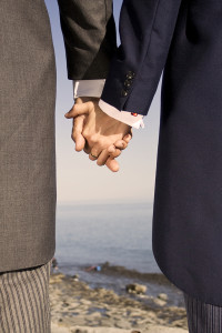 Two men in suits holding hands on the sea side